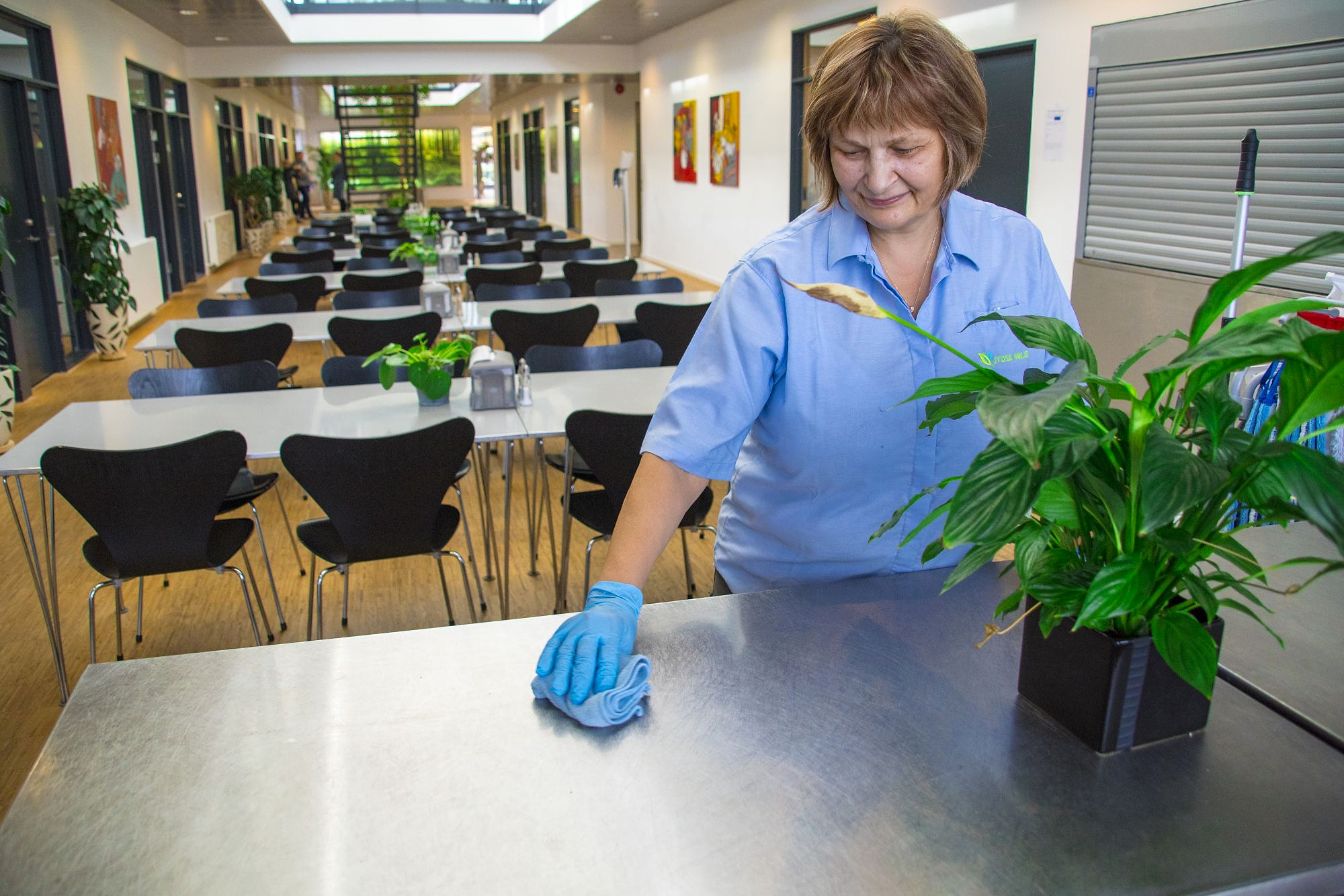 Medarbejder fra Jydsk Miljø tørrer borde af i en kantine